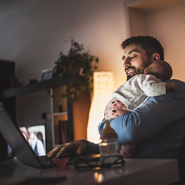 father learning on laptop with baby on shoulder